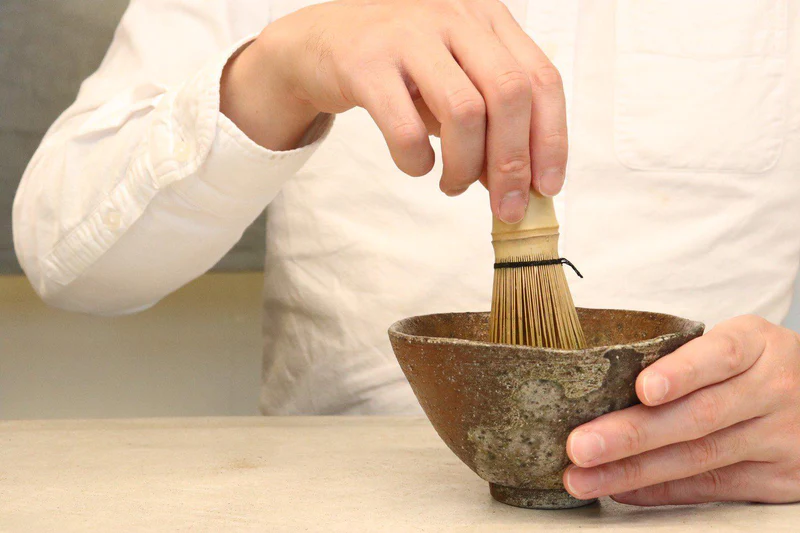YUGEN matcha being prepared with a white Takayama chasen matcha whisk