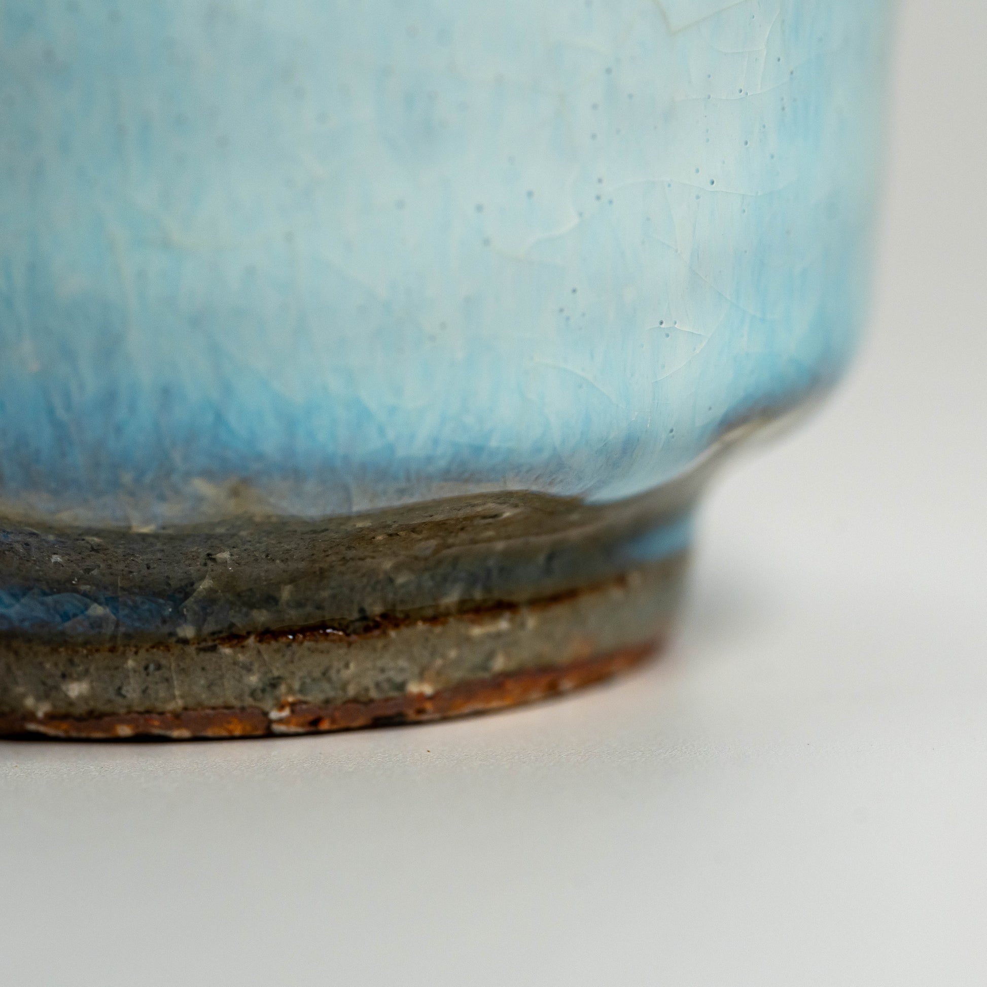 A close up of a blue Hagi yaki teacup on a white background