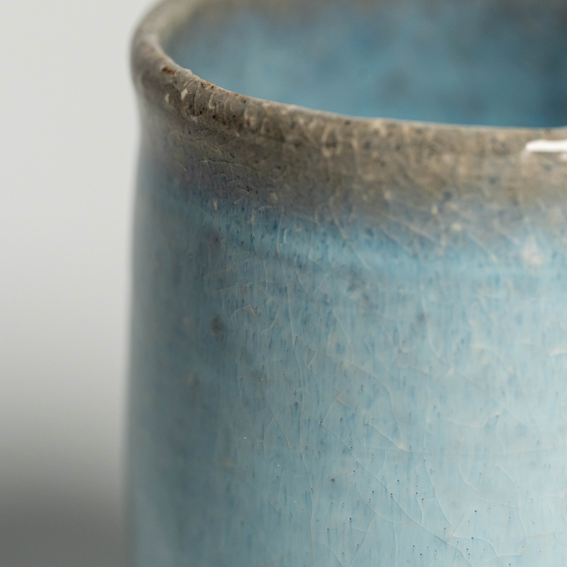 A close up of a blue Hagi yaki teacup on a white background