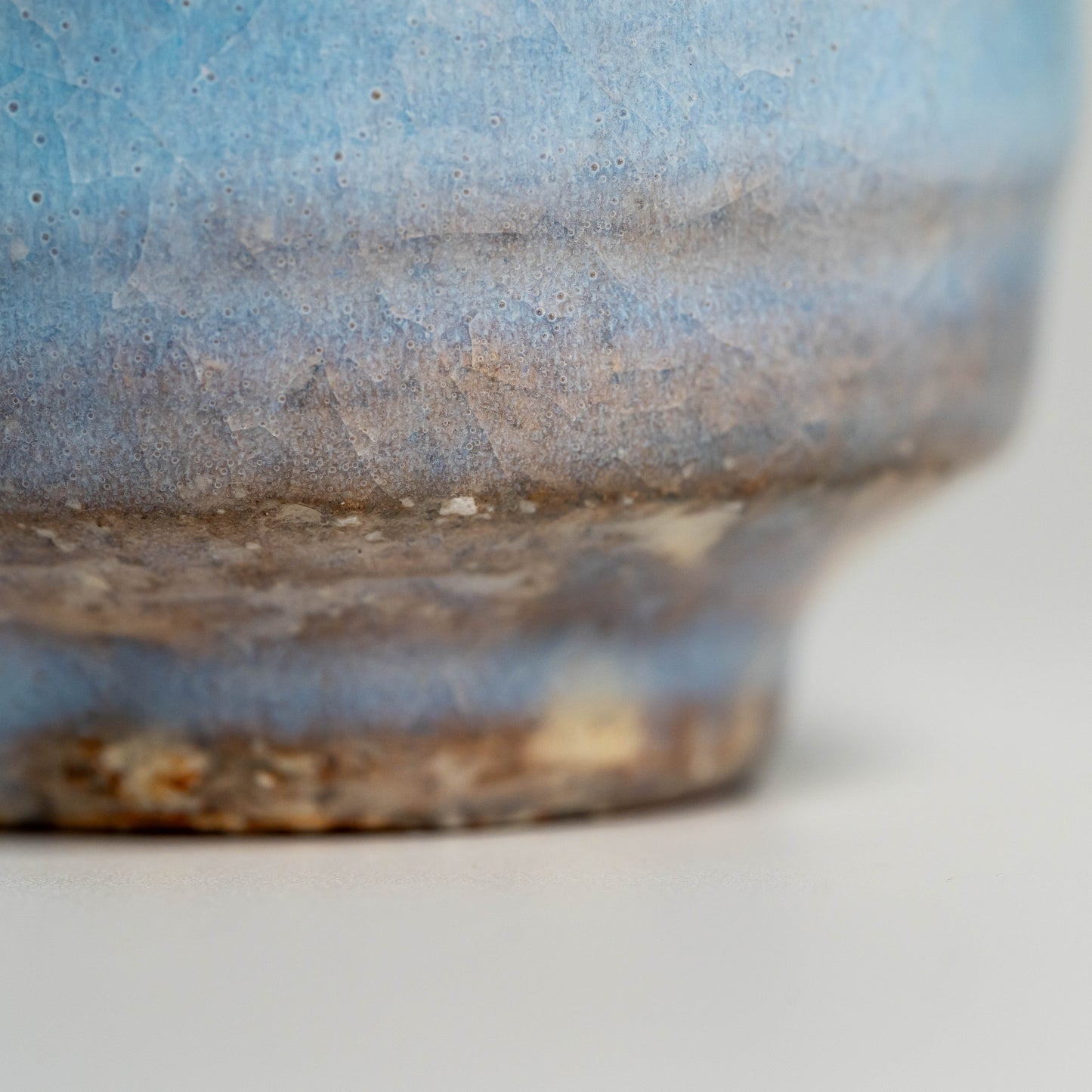 A close up of a blue Hagi yaki teacup on a white background