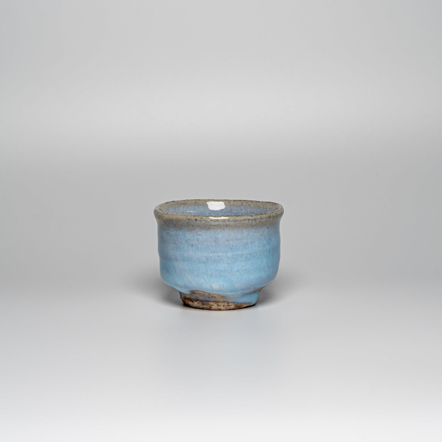 A blue Hagi yaki teacup on a white background