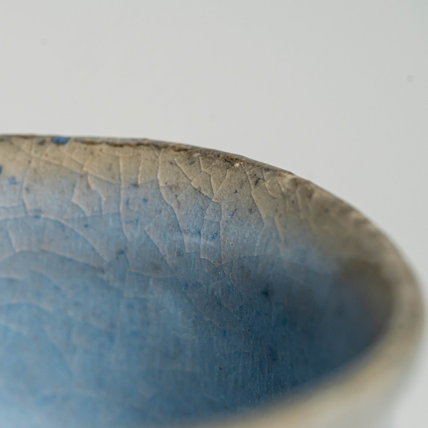A close up of a blue Hagi yaki teacup on a white background