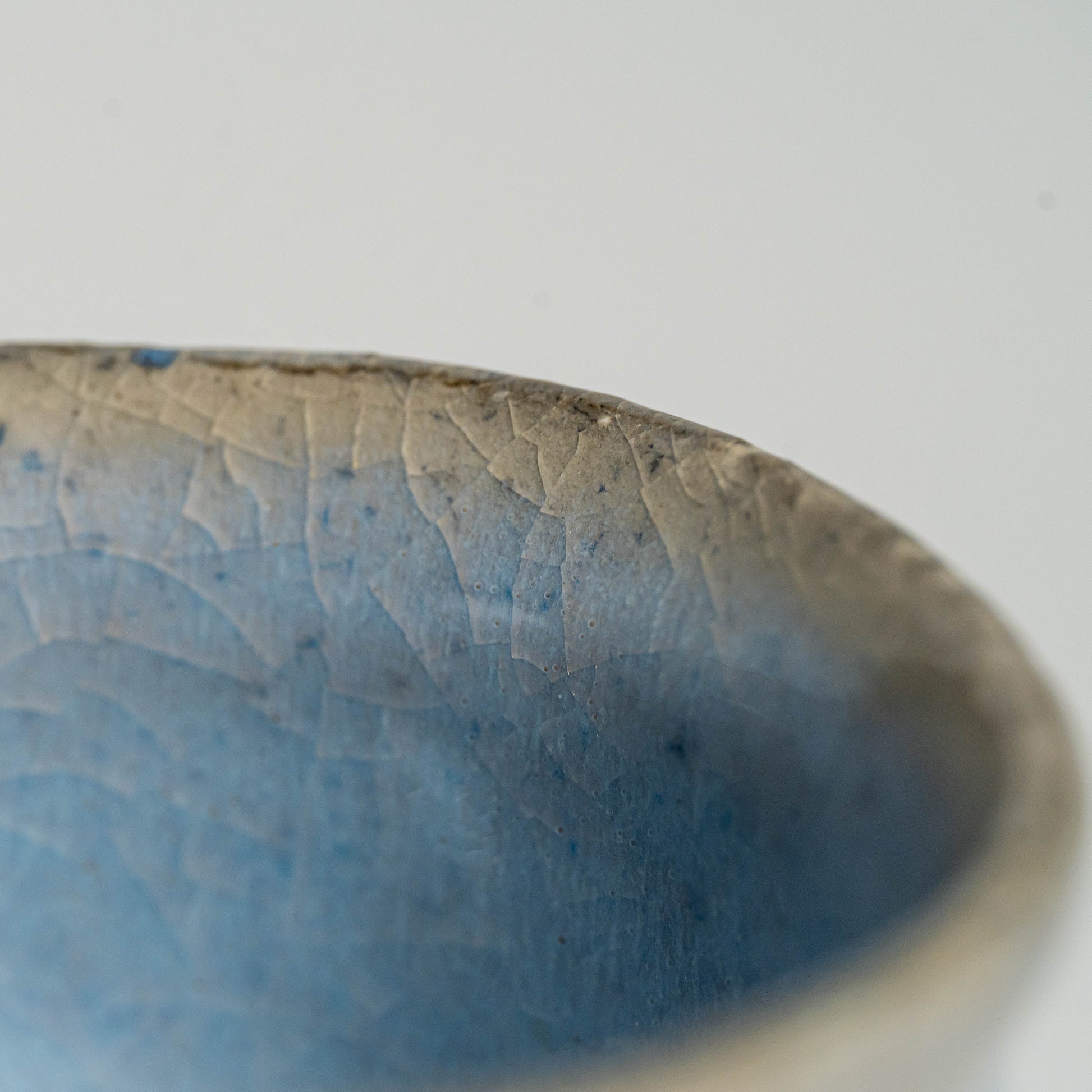 A close up of a blue Hagi yaki teacup on a white background