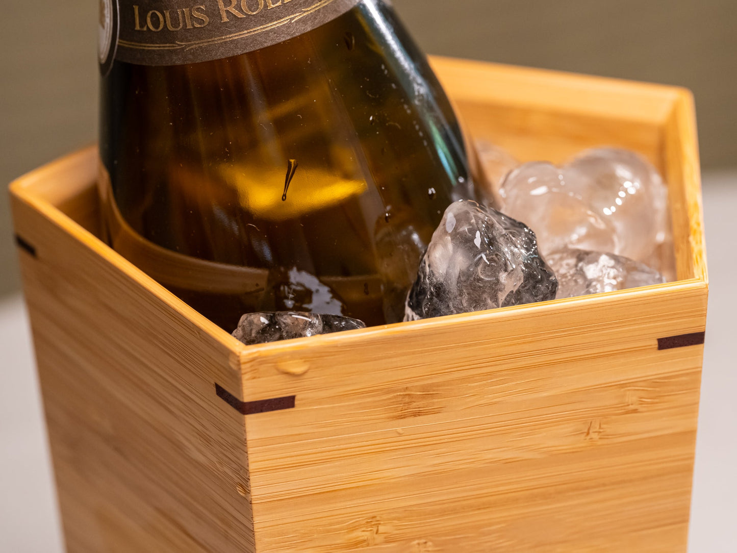A Japanese bamboo wine cooler filled with ice and a bottle of champagne