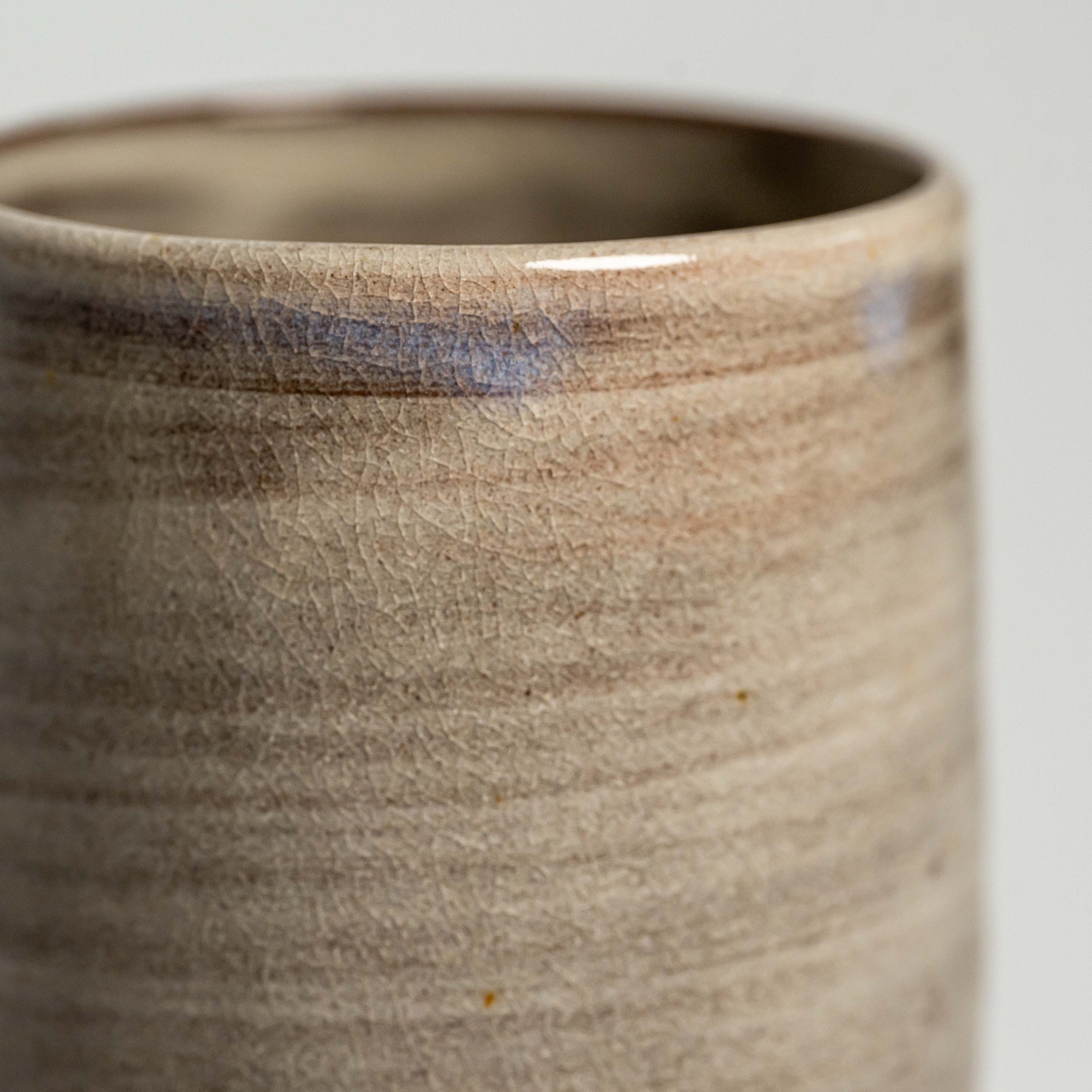 A close up of a brown Hagi yaki teacup on a white background