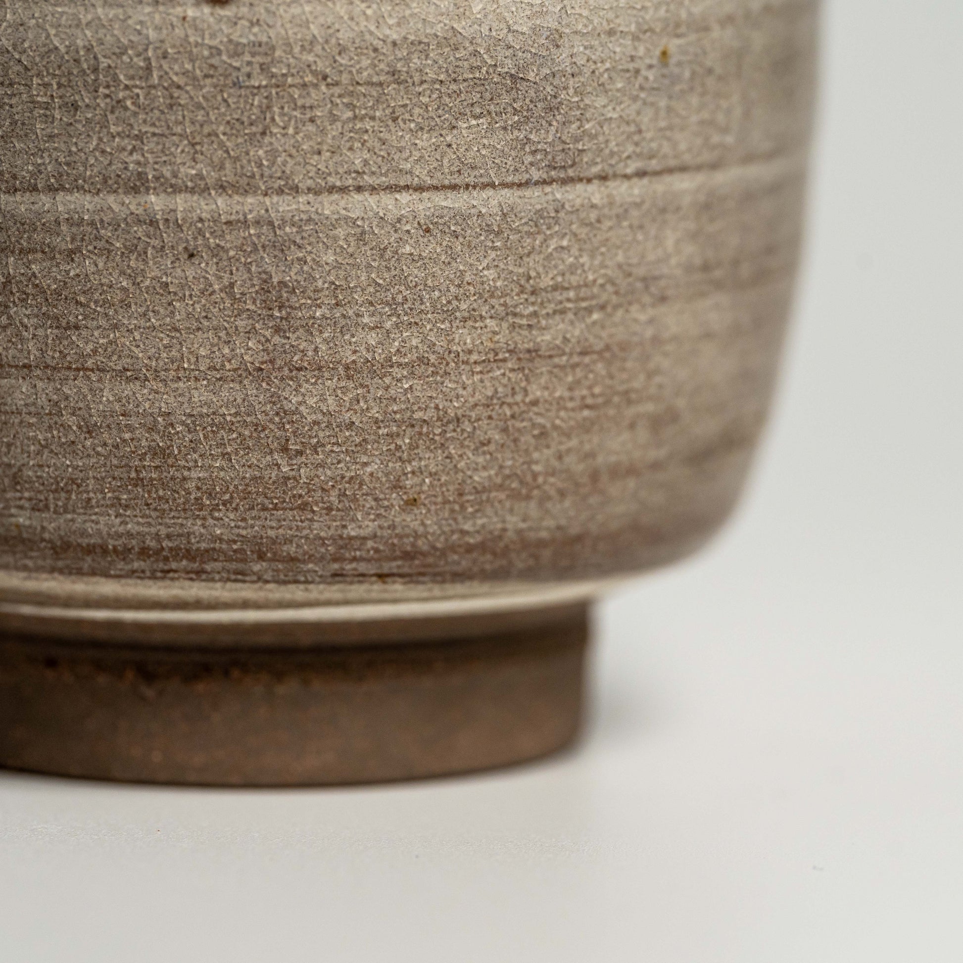 A close up of a brown Hagi yaki teacup on a white background