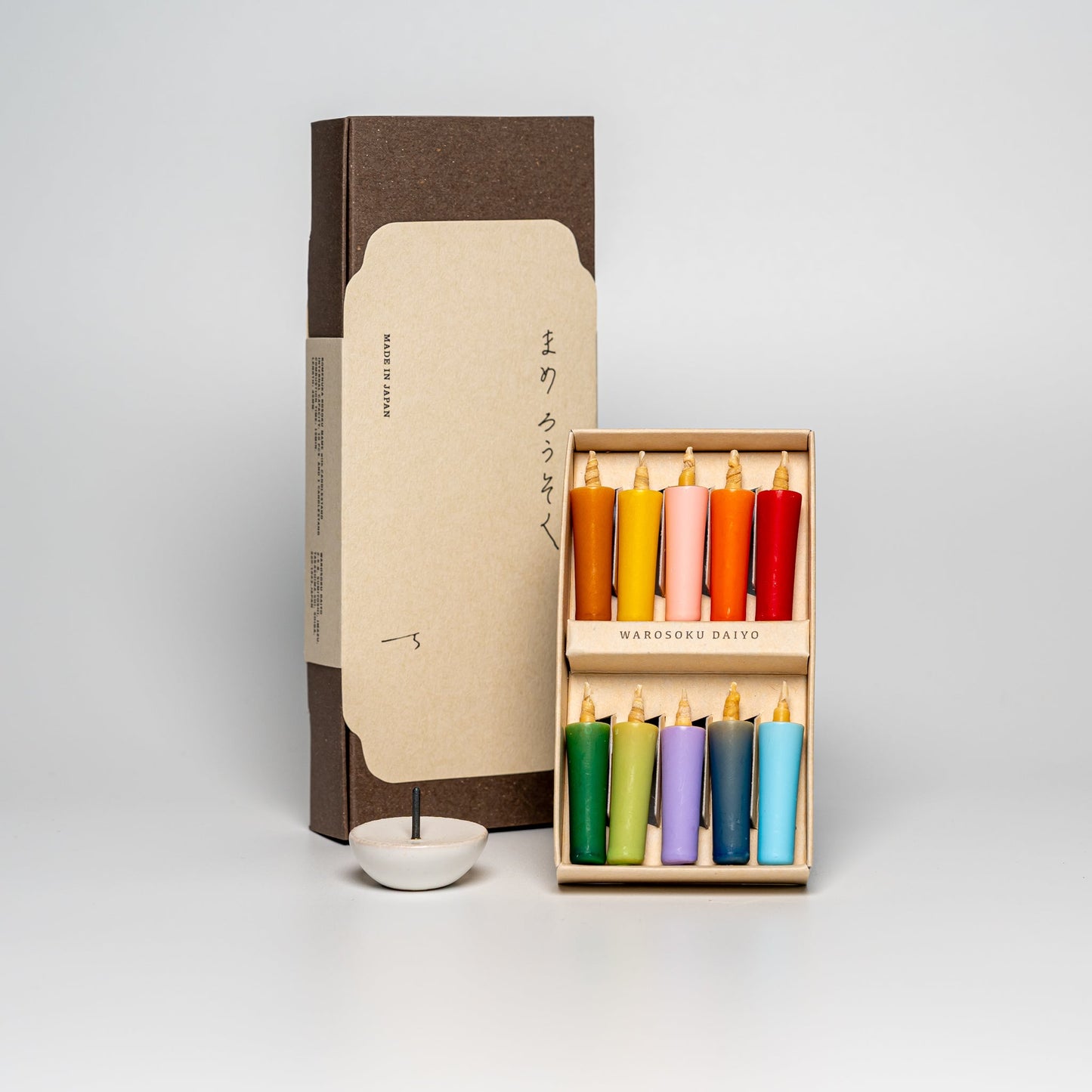 A box of vivid dyed rice wax candles on a white background