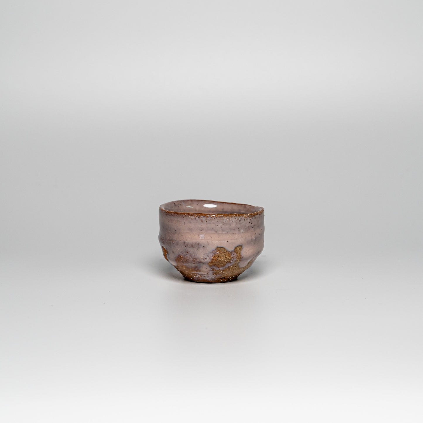 A pink Hagi yaki sake cup on a white background