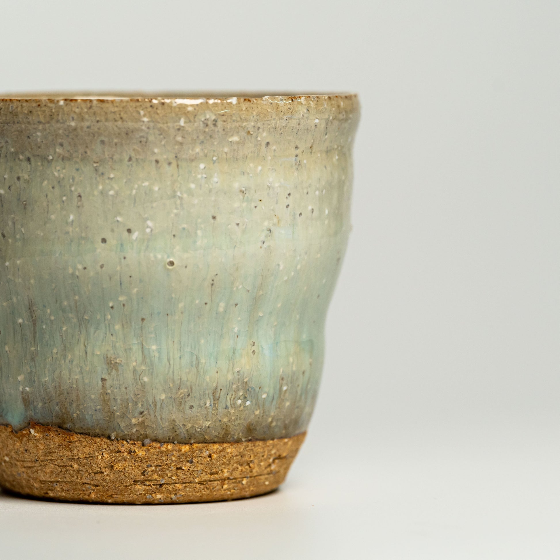 A close up of a green Hagi yaki shochu cup on a white background