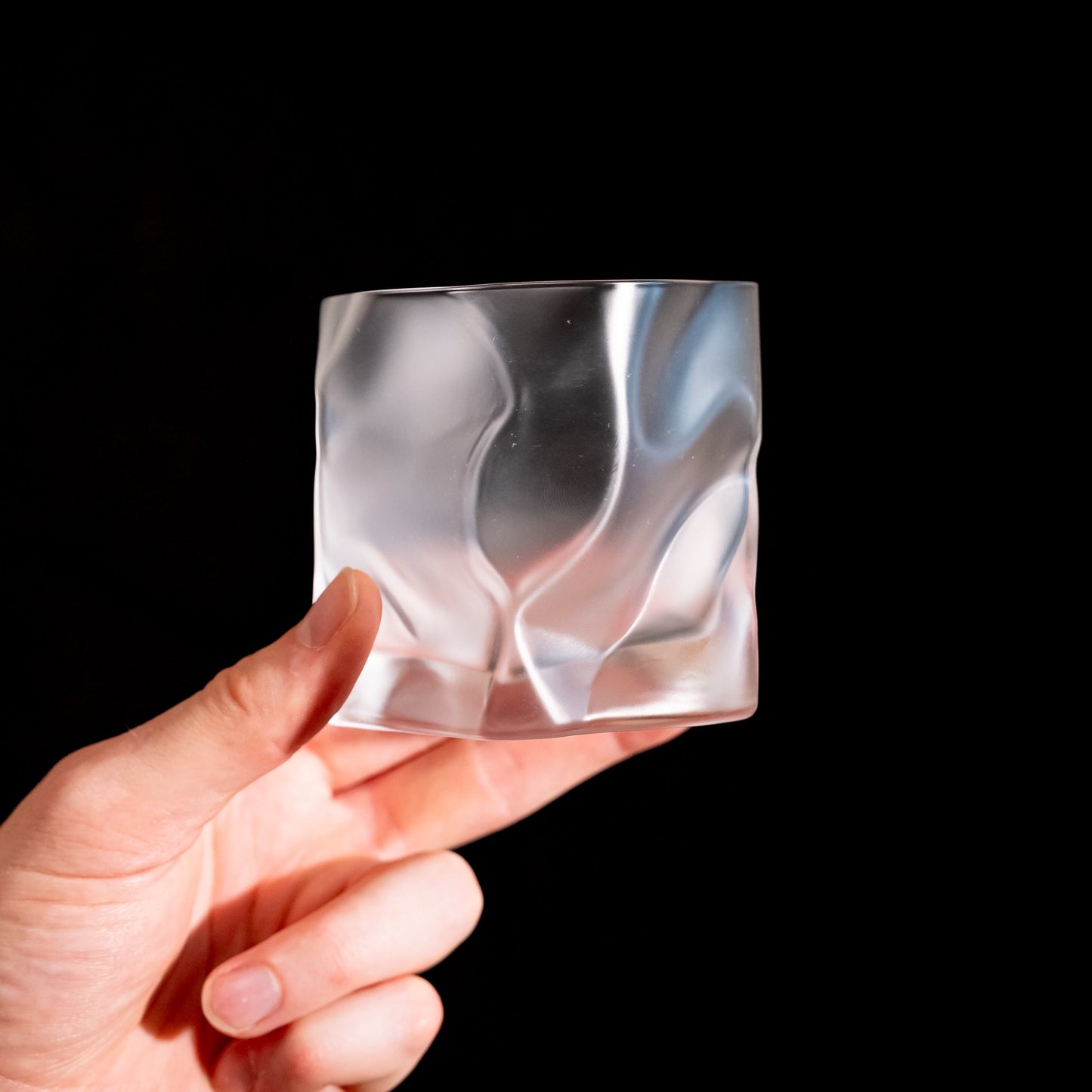 A crumpled whiskey glass by Kimura Glass held in hand