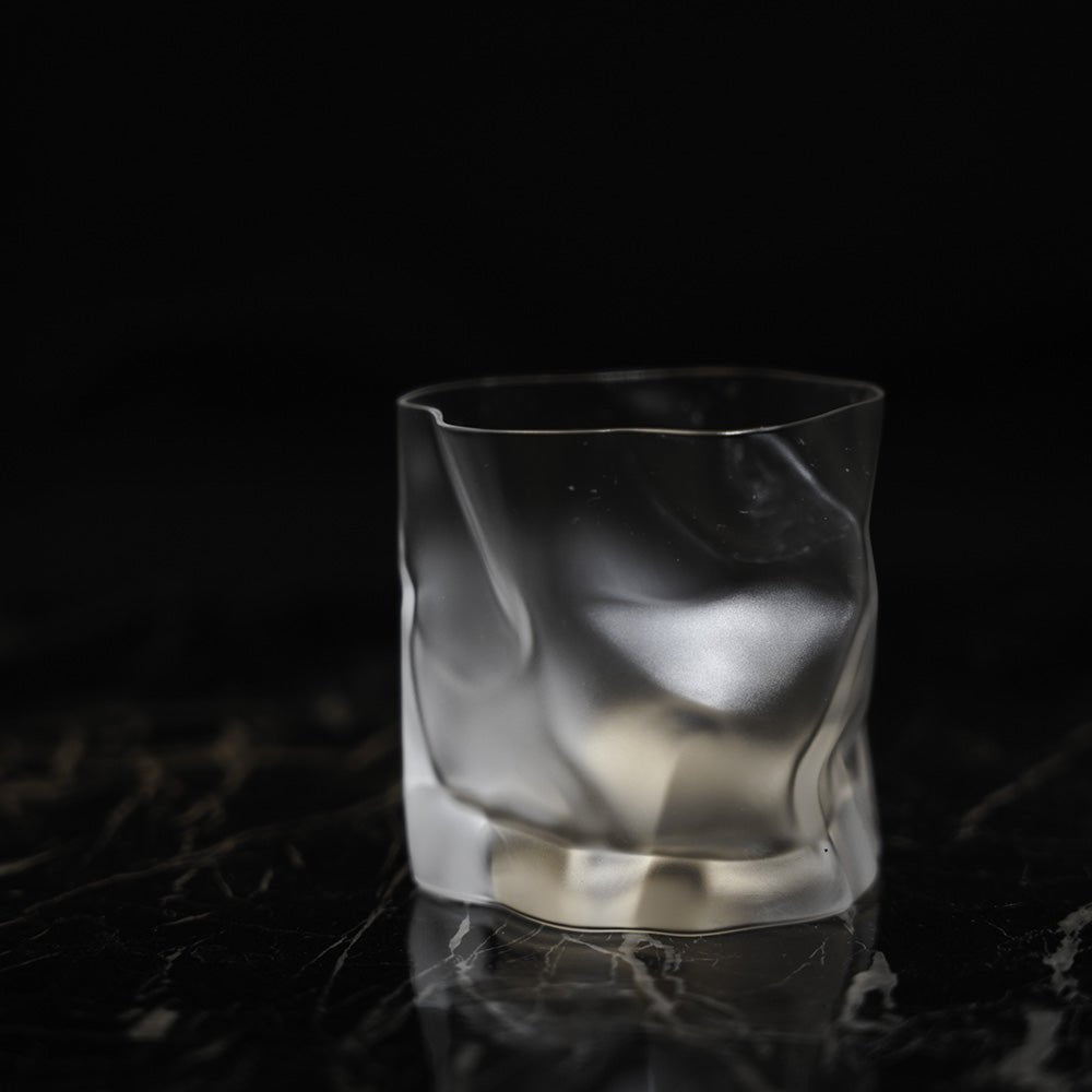 A frosted crumple whiskey glass on a black background
