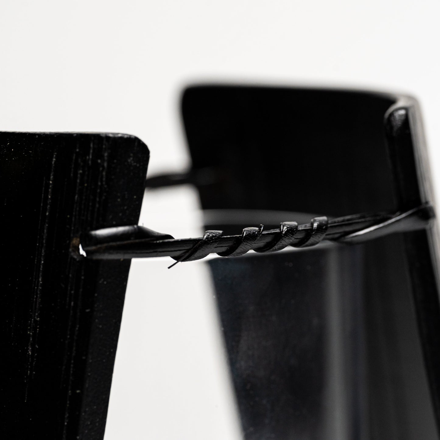 A close up of an empty black bamboo Noshi flower vase on a white background