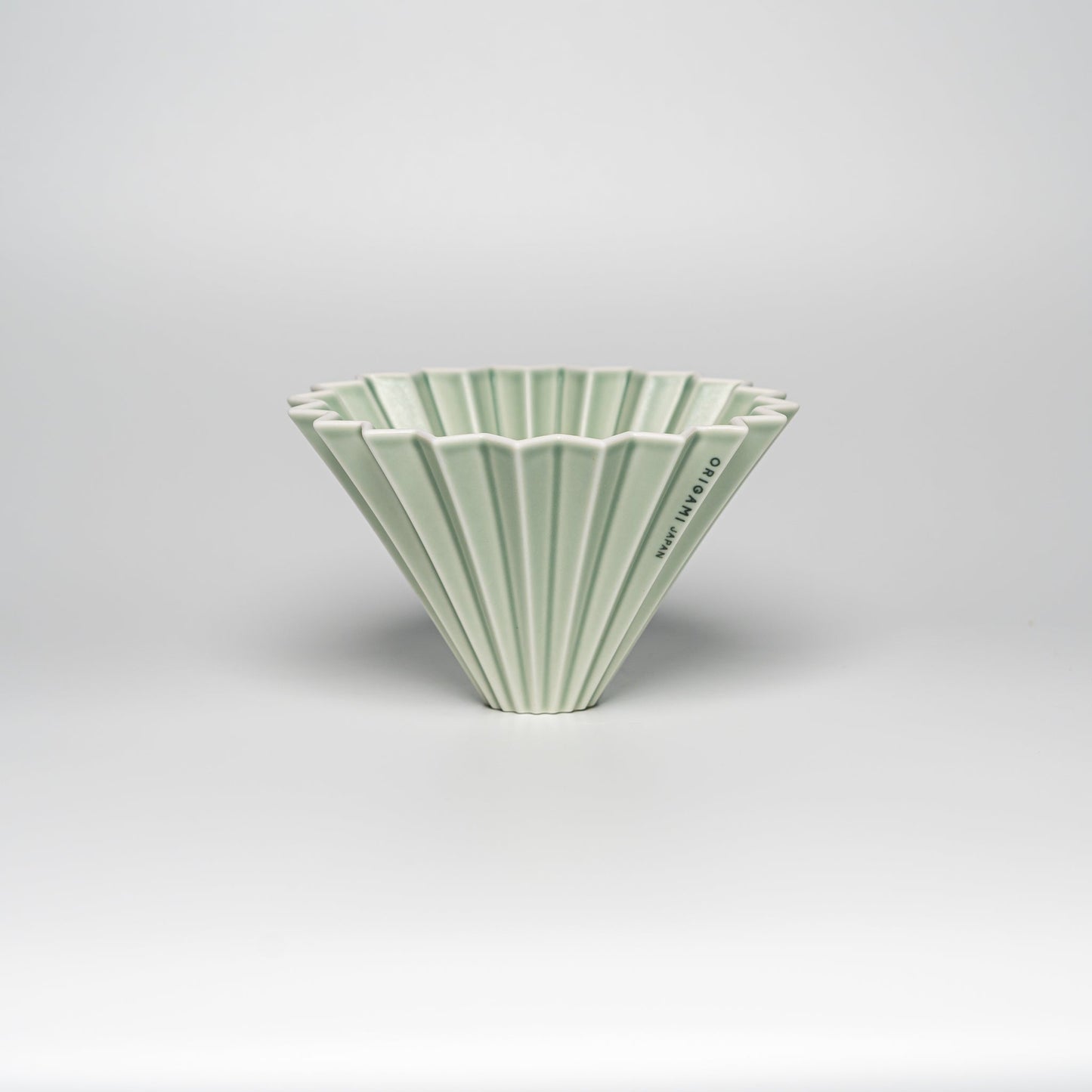 A matte green ORIGAMI coffee dripper on a white background
