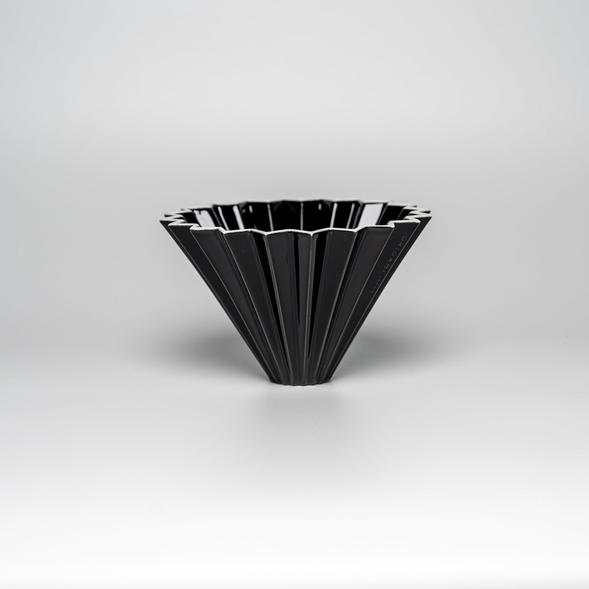 A black ORIGAMI coffee dripper on a white background