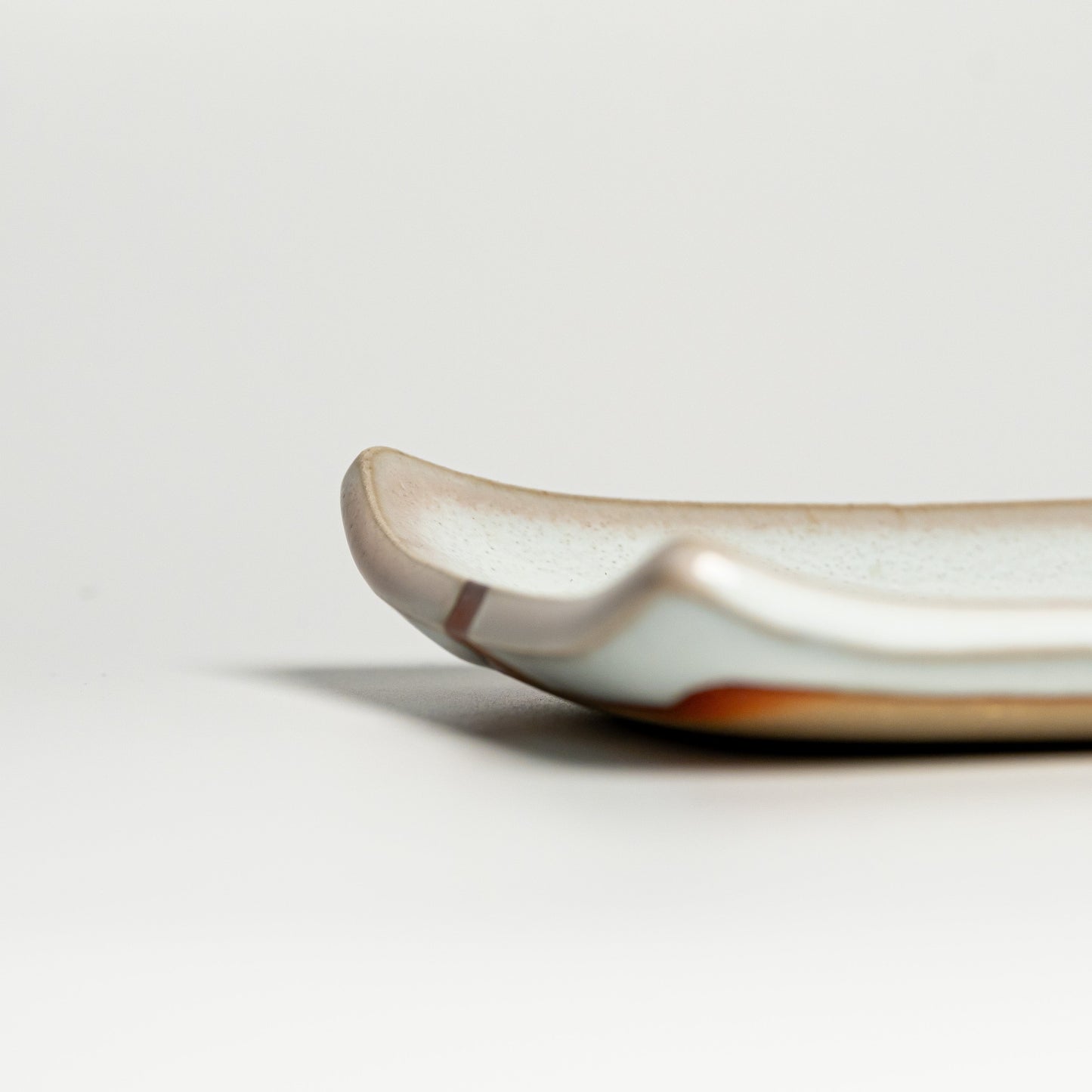 A close up of a white Hagi yaki plate on a white background