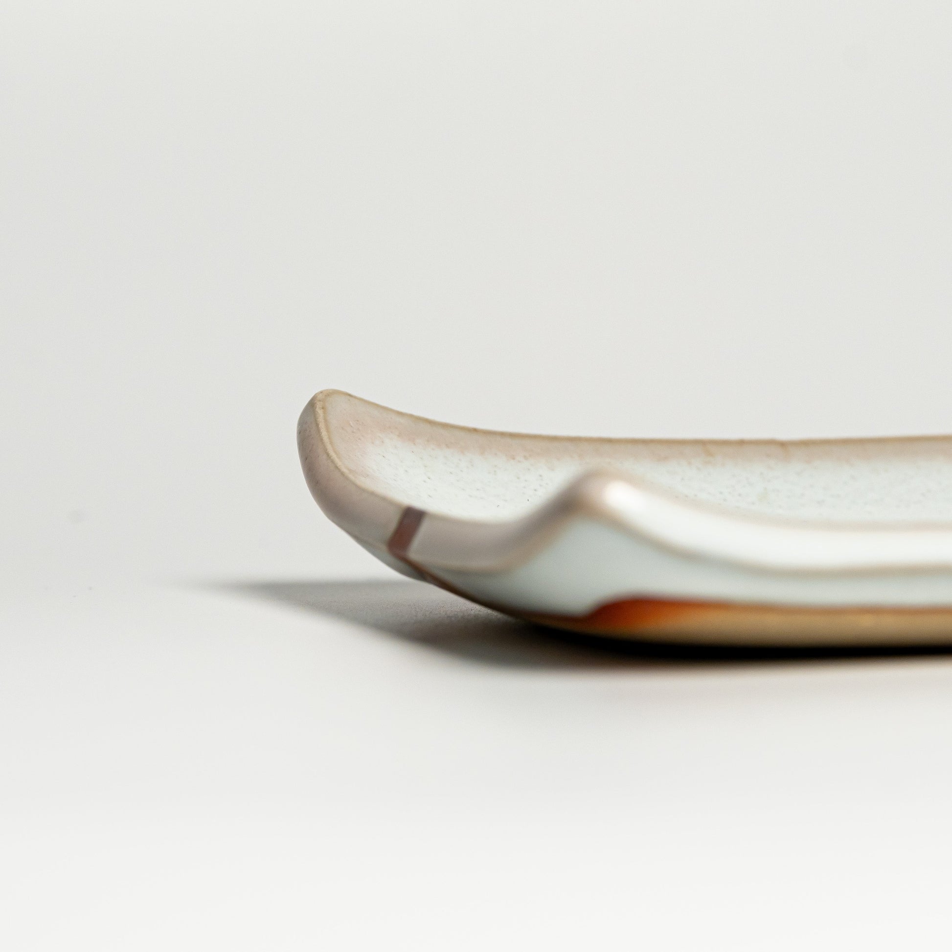 A close up of a white Hagi yaki plate on a white background