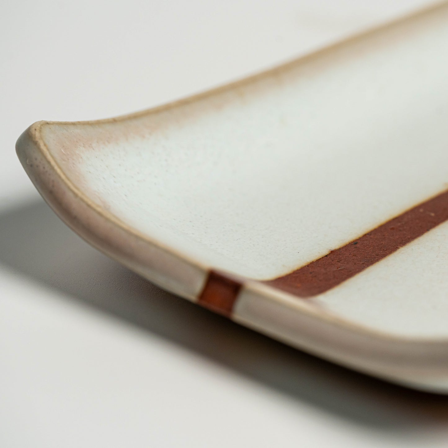 A close up of a white Hagi yaki plate on a white background