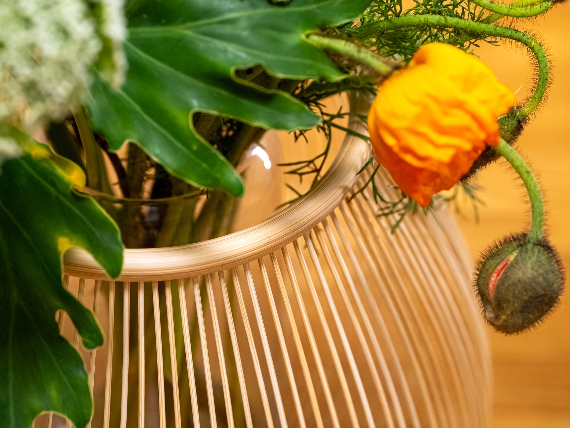 A close up of a Japanese bamboo vase with a contemporary flower arrangement