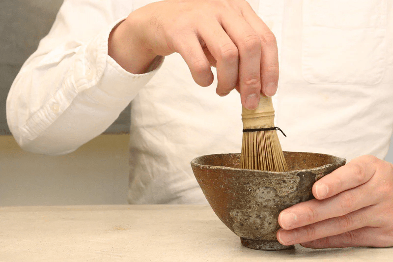 A Takayama chasen tea whisk being used to whisk matcha in a bowl