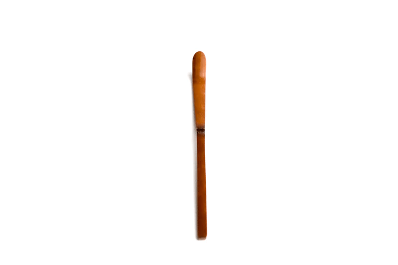 A close up of a soot bamboo tea scoop on a white background
