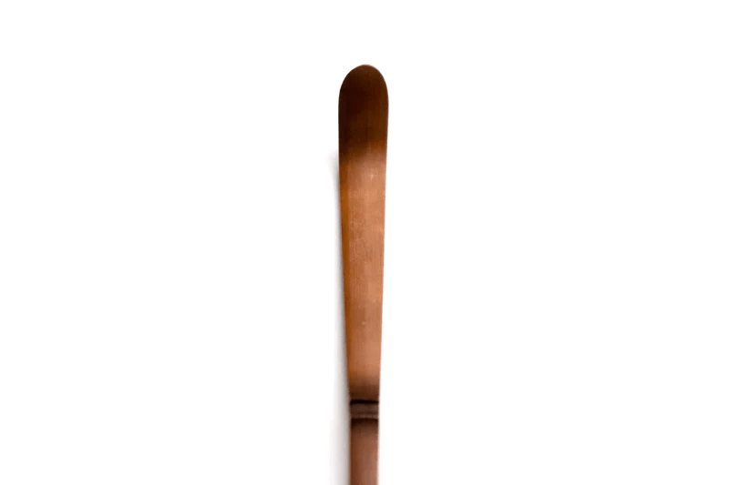 A close up of a soot bamboo tea scoop on a white background
