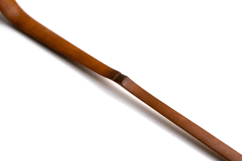 A close up of a soot bamboo tea scoop on a white background
