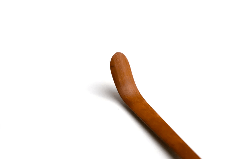 A close up of a soot bamboo tea scoop on a white background