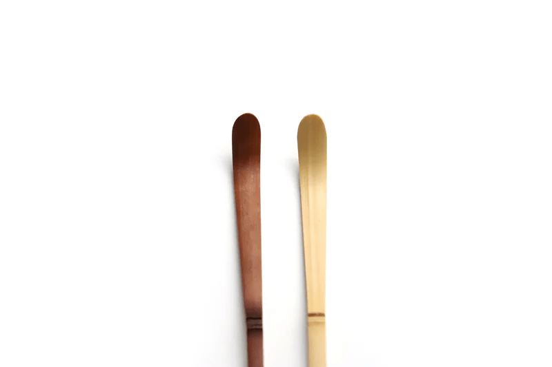 A close up of a bamboo tea scoops on a white background