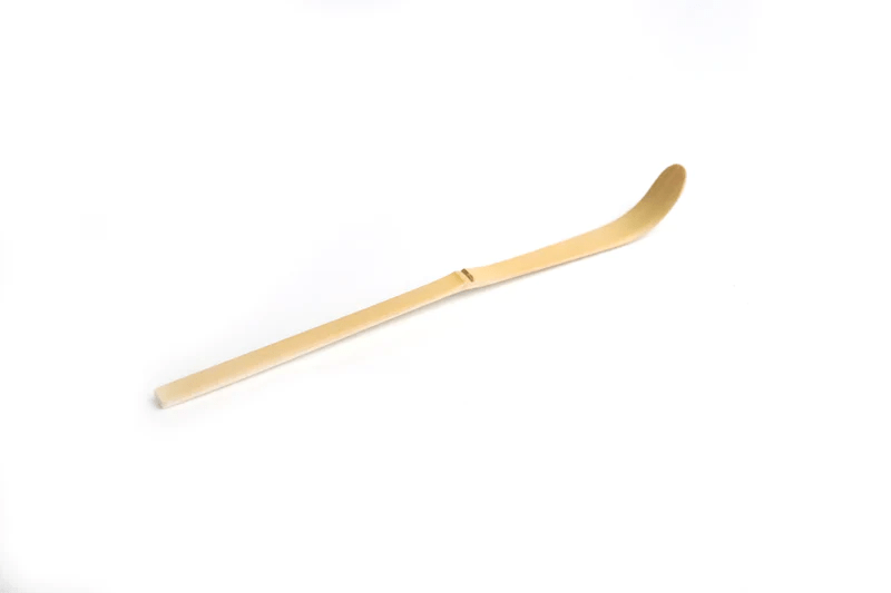 A white bamboo tea scoop on a white background