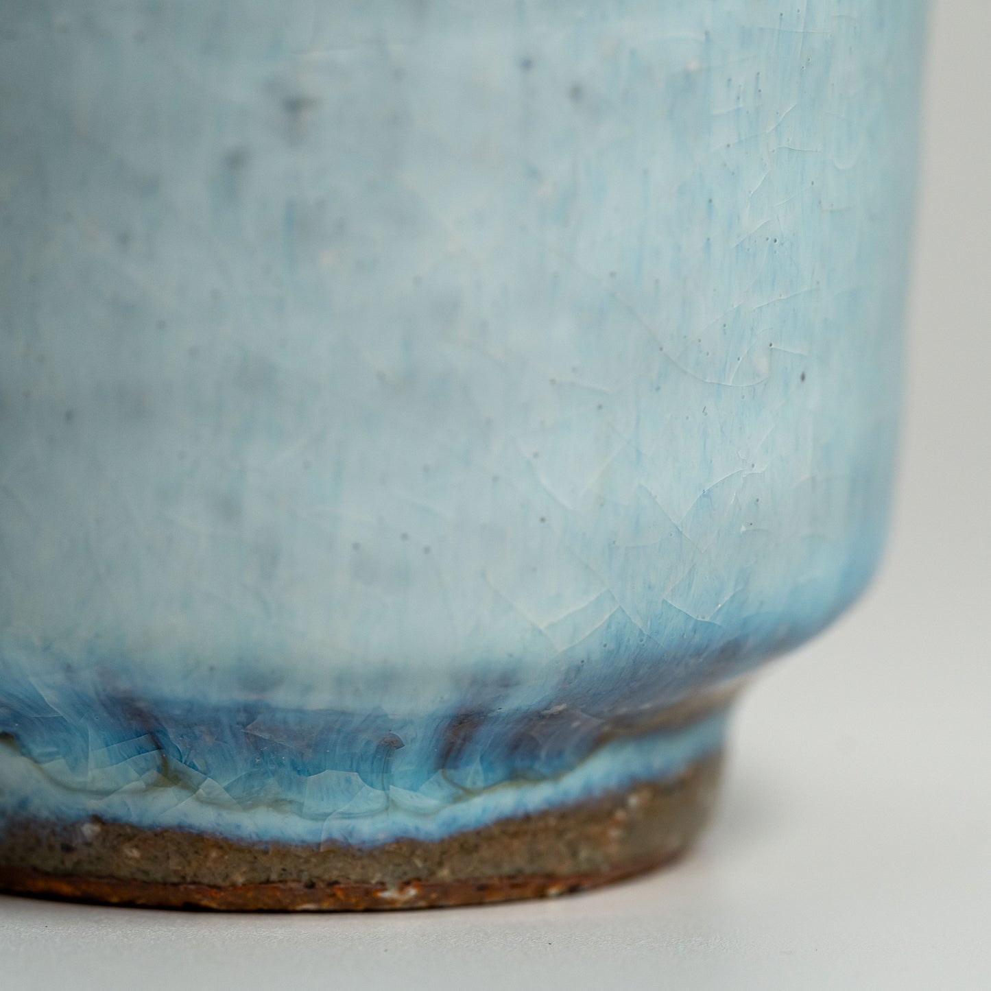 A close up of a blue Hagi yaki teacup on a white background
