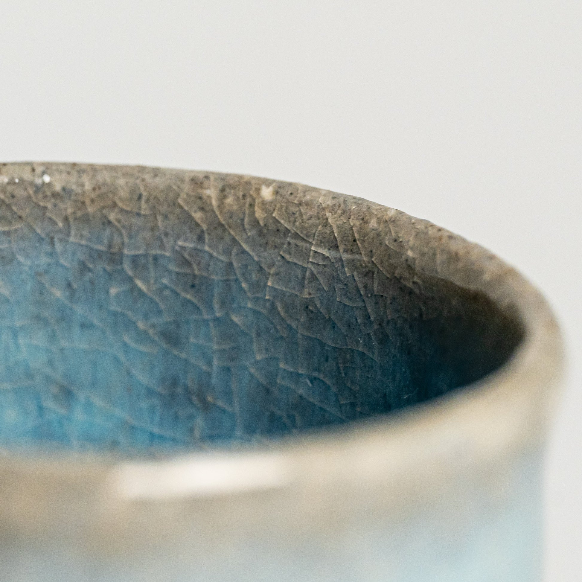 A close up of a blue Hagi yaki teacup on a white background