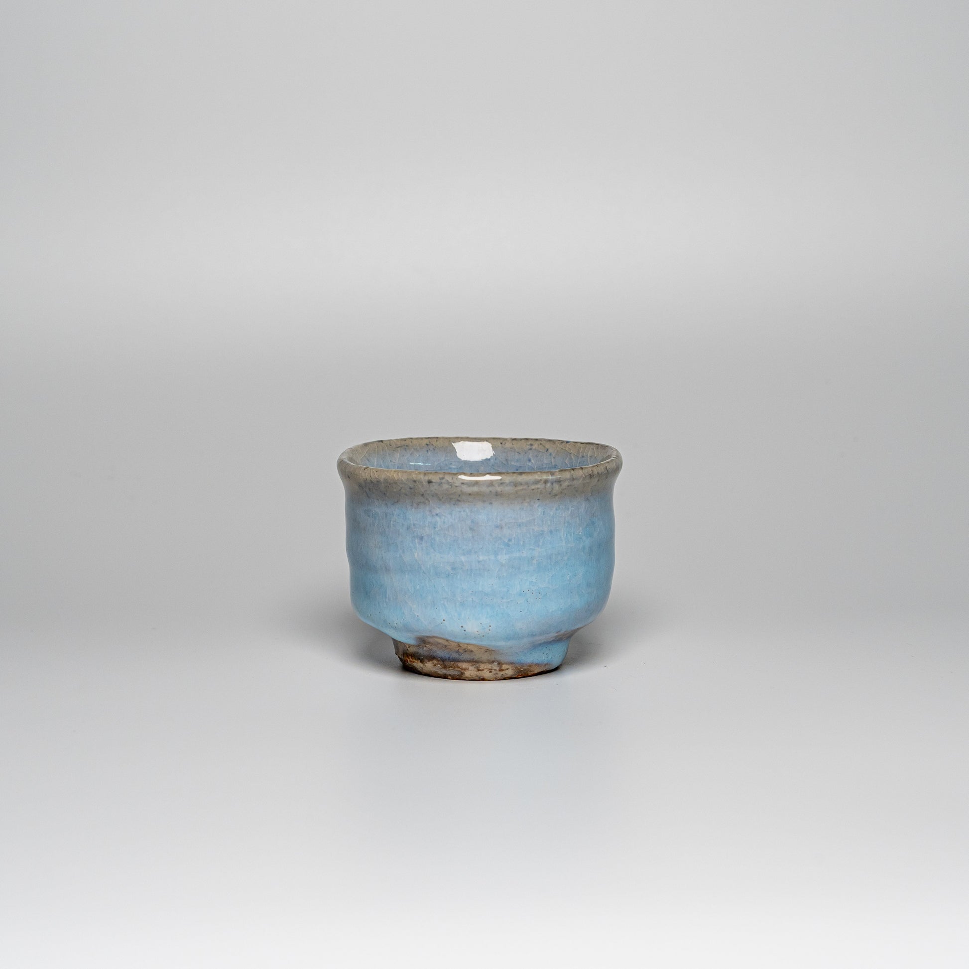 A blue Hagi yaki teacup on a white background