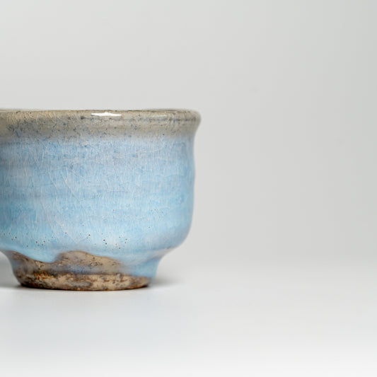 A blue Hagi yaki teacup on a white background