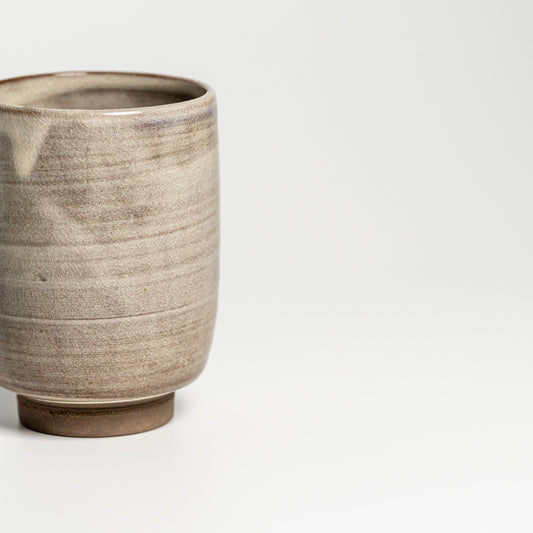A brown Hagi yaki teacup on a white background