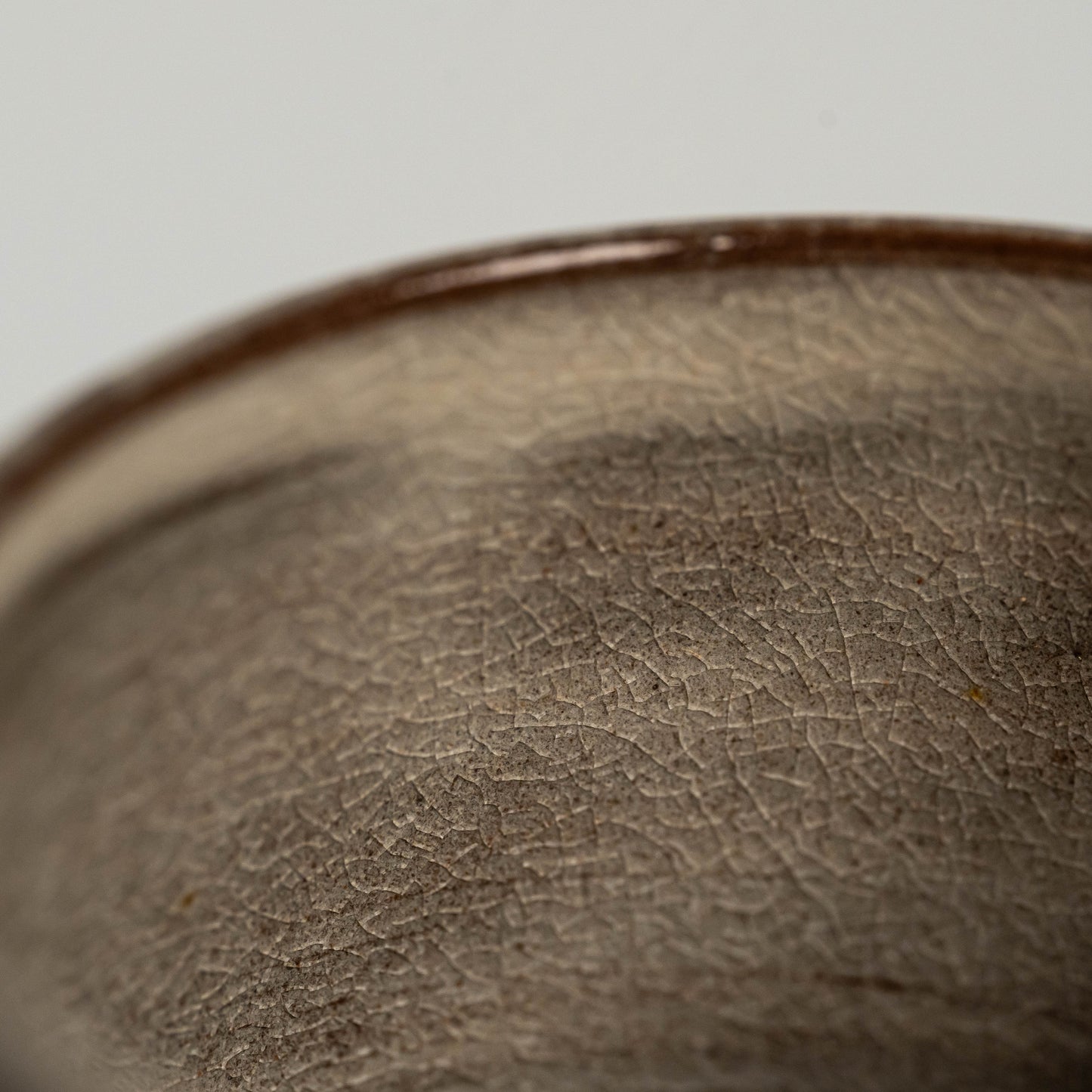 A close up of a brown Hagi yaki teacup on a white background