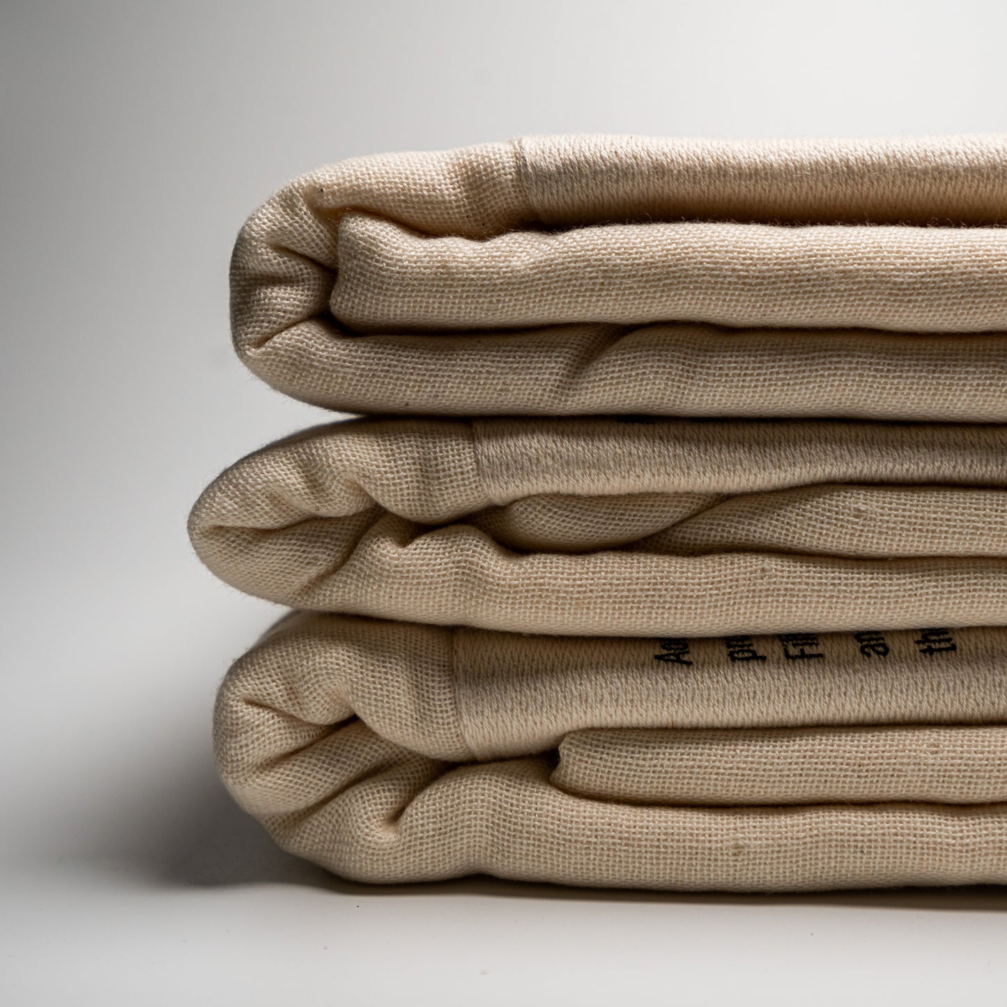 A stack of natural Filhiba bath towels on a white background