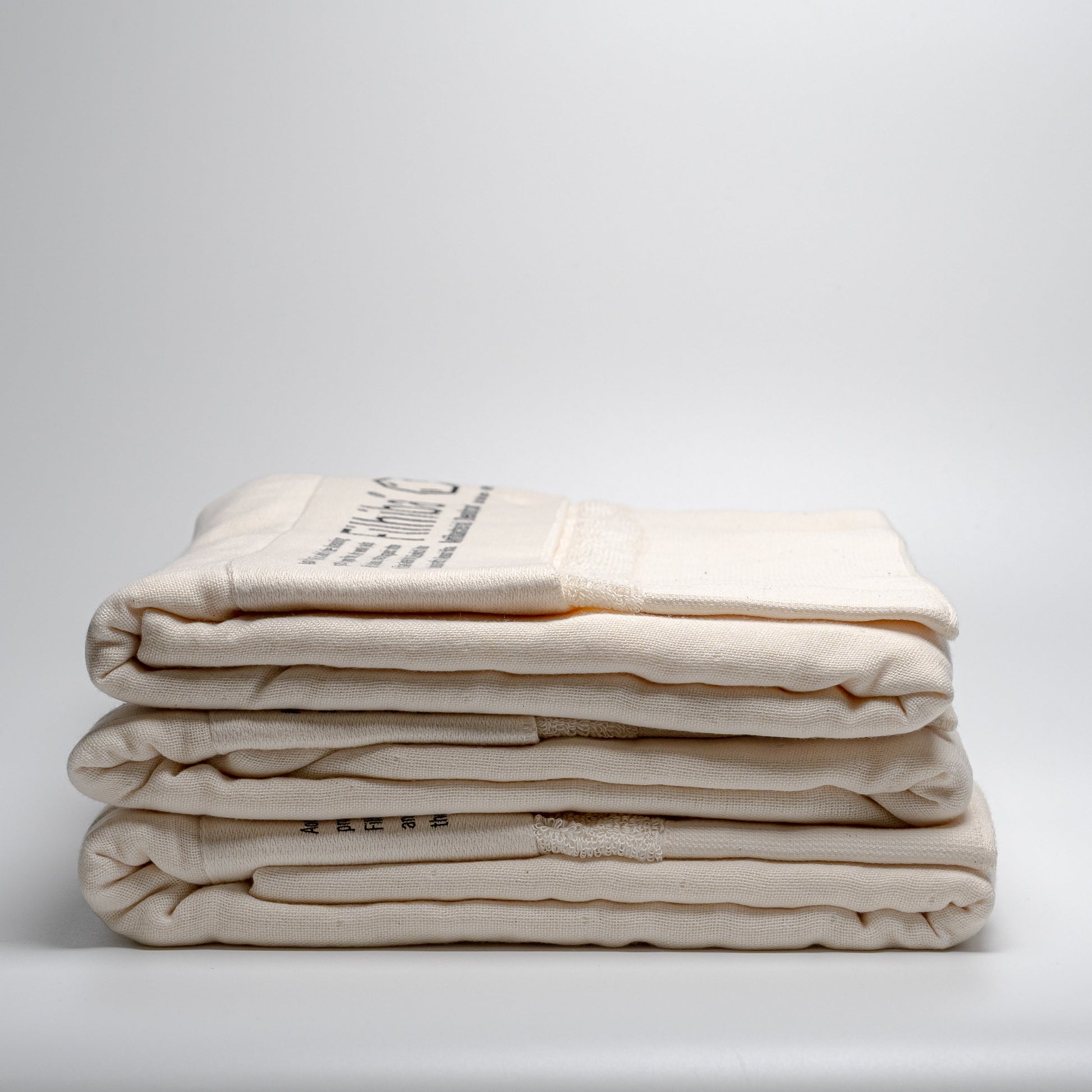 A stack of natural Filhiba bath towels on a white background