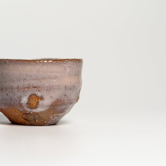 A pink Hagi yaki sake cup on a white background