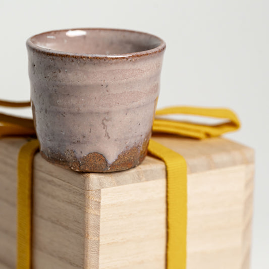 A pink Hagi yaki sake cup on its wooden box