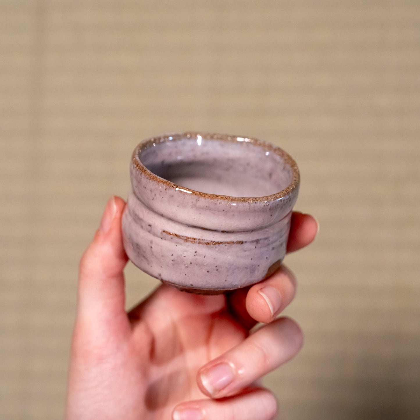 A Japanese ceramic Hagi yaki sake cup held in hand