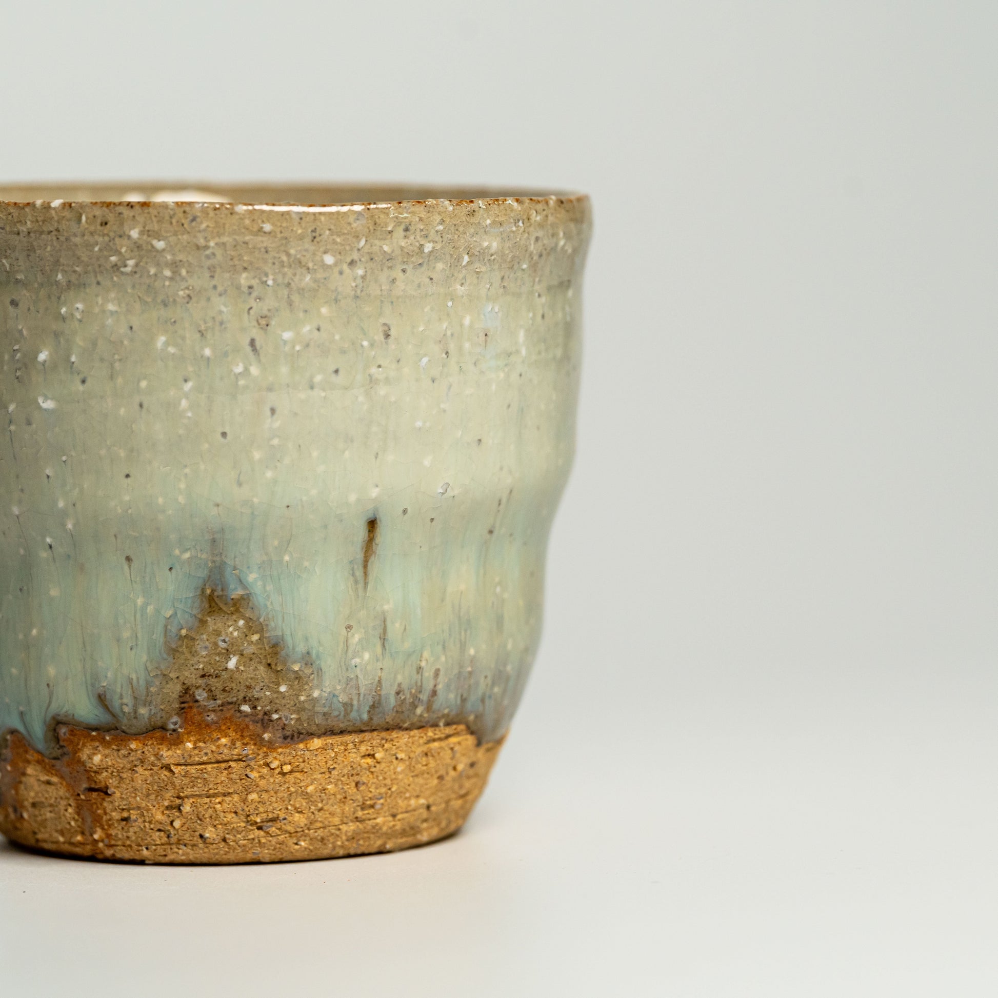 A close up of a green Hagi yaki shochu cup on a white background