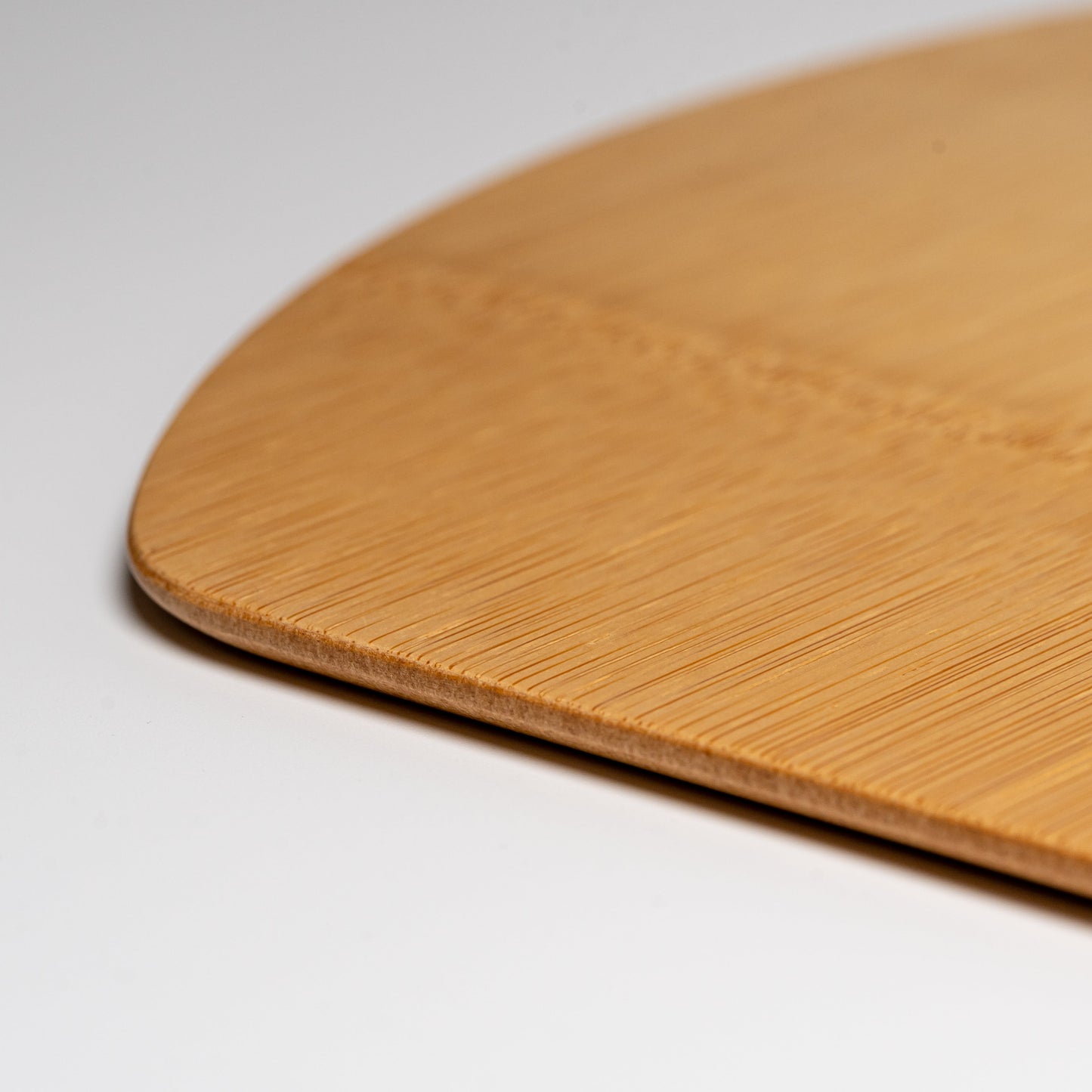 A close up of a bamboo half moon placemat on a white background