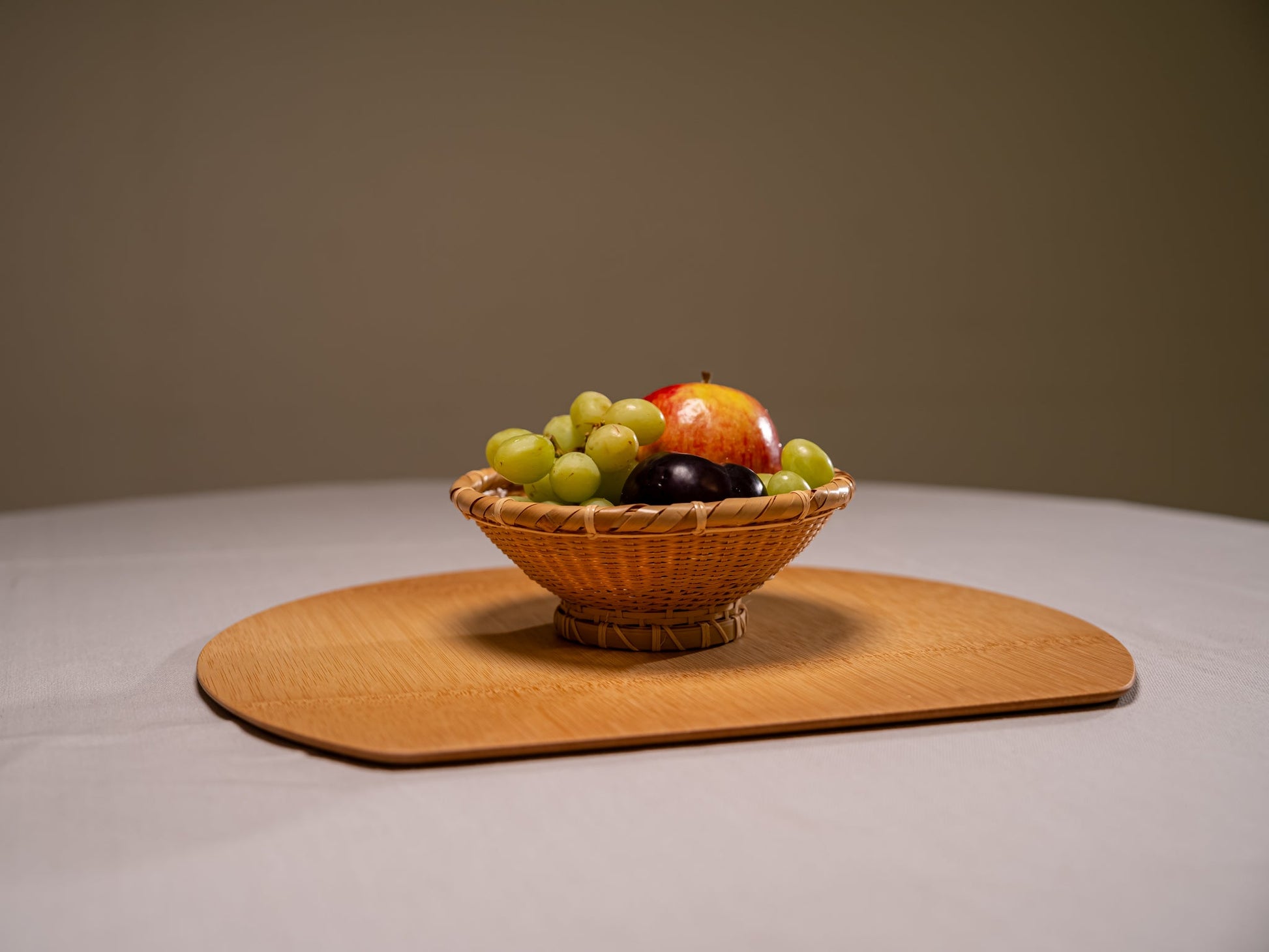 A Japanese bamboo half moon placemat with a bowl of fruit on top