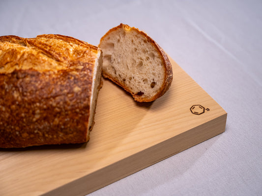 Cul de Sac's hiba wood chopping board with a sliced load of bread