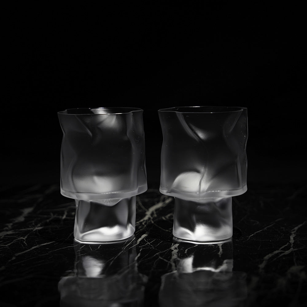 Two frosted crumple cocktail glasses on a black background