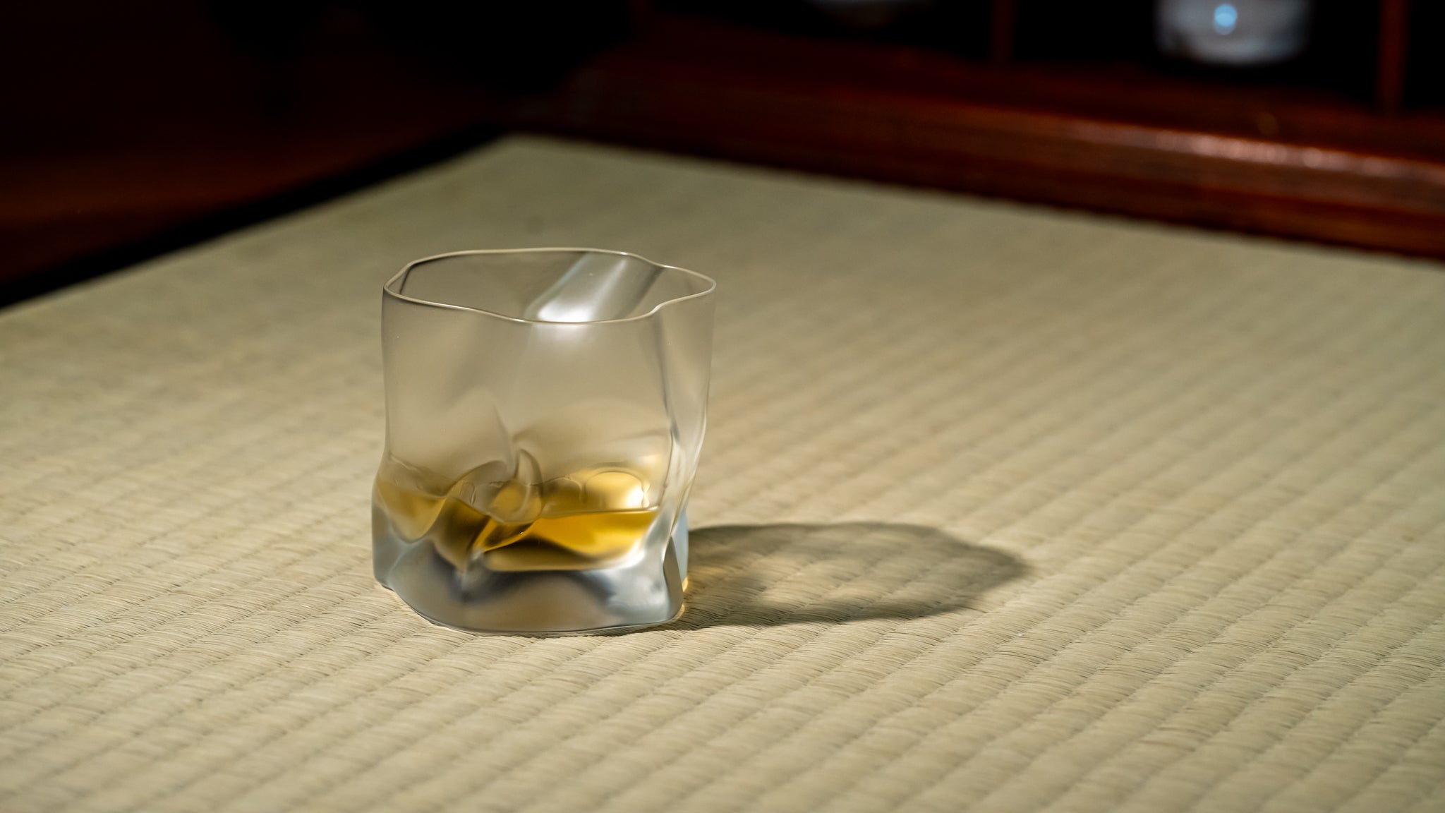 A crumpled whiskey glass by Kimura Glass on a tatami mat