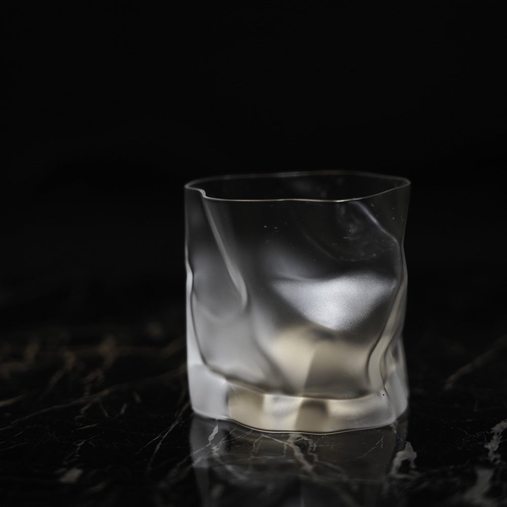 A frosted crumple whiskey glass on a black background