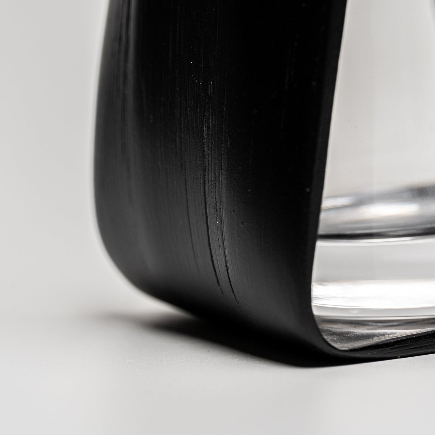 A close up of the bottom of an empty black bamboo Noshi flower vase on a white background