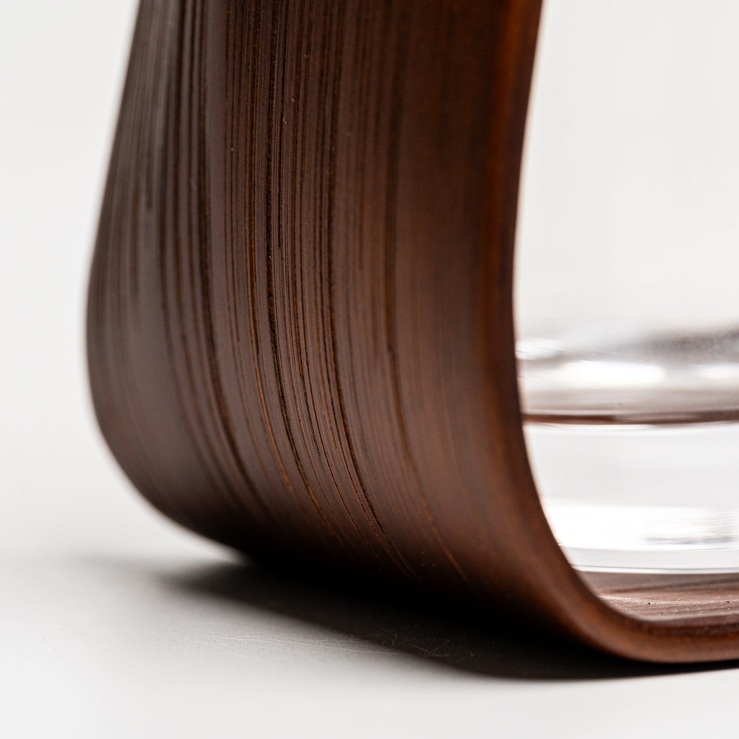 A close up of the bottom of an empty brown bamboo Noshi flower vase on a white background
