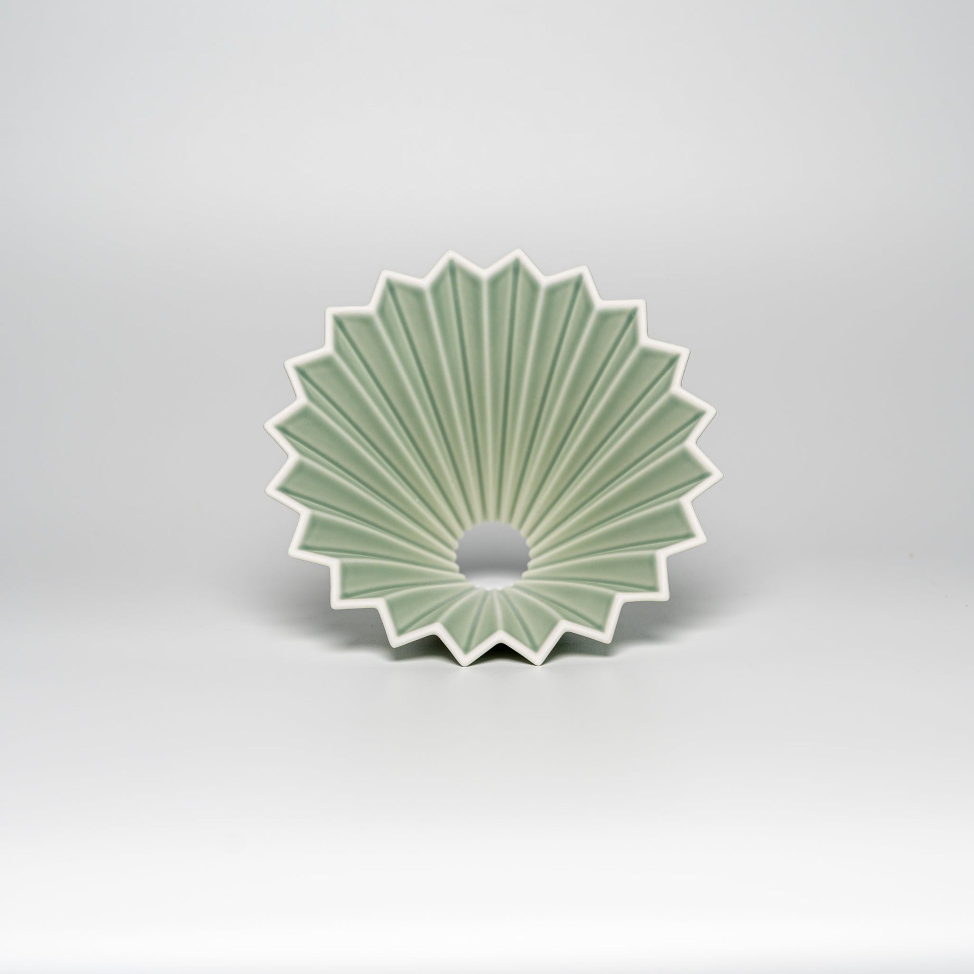 A matte green ORIGAMI coffee dripper on a white background